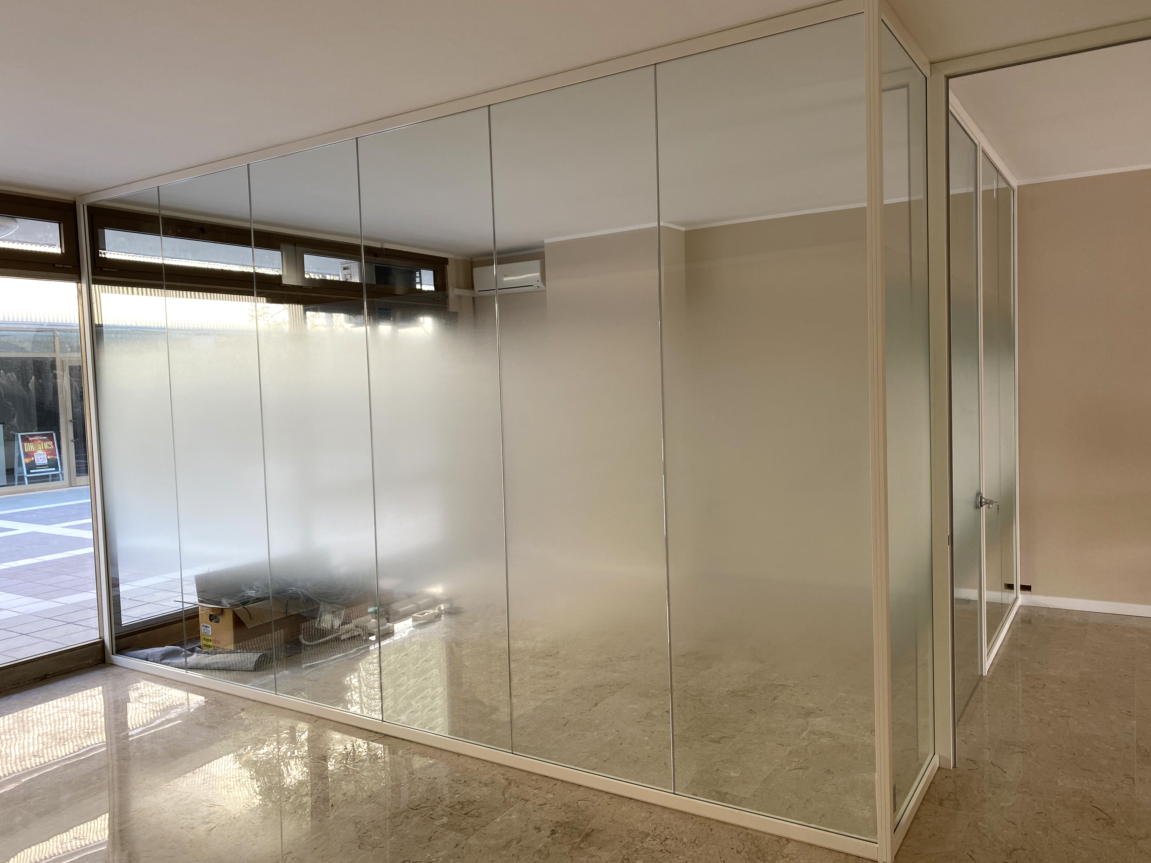 Zu sehen ist ein Büro mit einem verglasten Meeting-Raum, der durch eine Milchglasfolie teilweise vor Blicken geschützt wird.