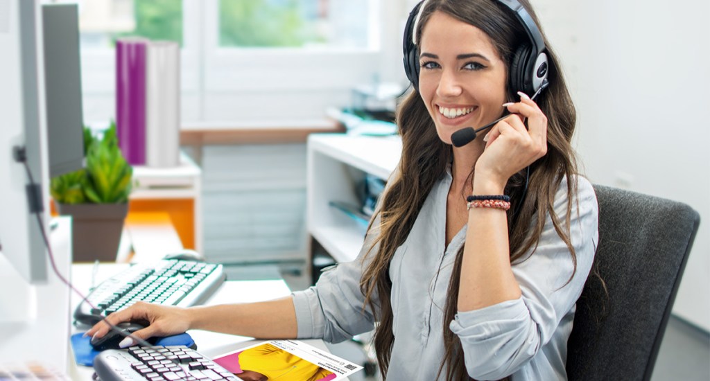 Lady in an office with a headset on, looking at the camera
