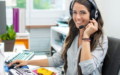 Lady in an office with a headset on, looking at the camera